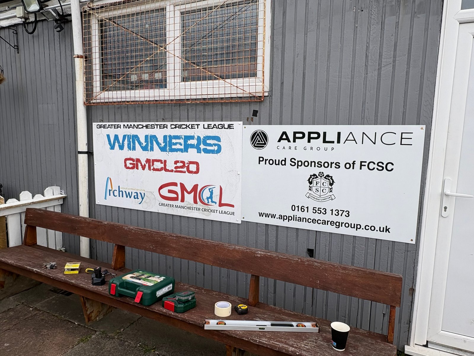 Flixton Cricket Club sponsor boards — GMCL Winners banner and Appliance Care Group sponsor panel